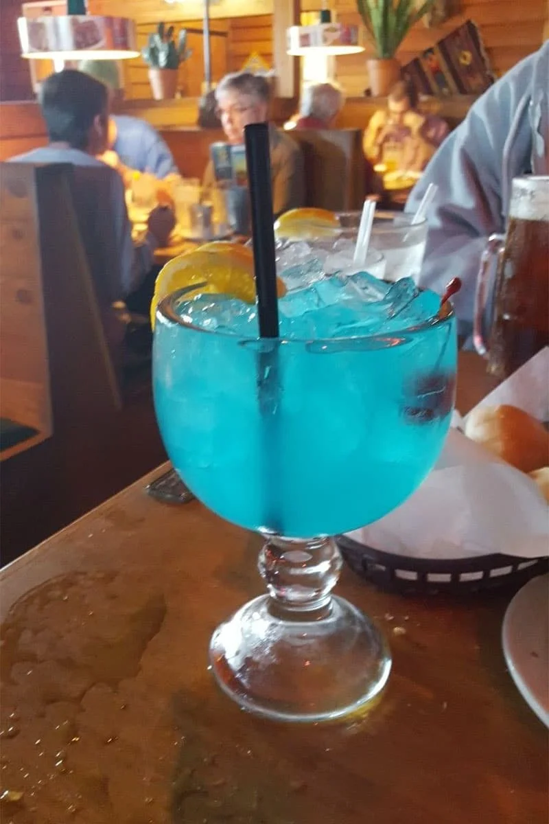 Close up of Texas Roadhouse style Blue Crush Lemonade recipe ingredients - lemons, blue curaçao, sweet and sour mix